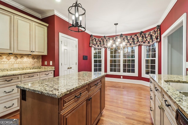 kitchen with backsplash, cream cabinets, hanging light fixtures, and ornamental molding