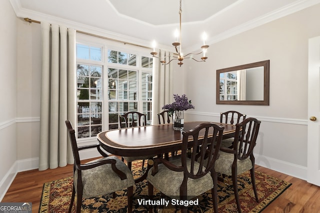 dining area with hardwood / wood-style flooring, crown molding, a tray ceiling, and a chandelier