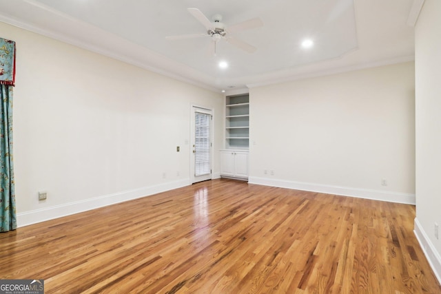 unfurnished room with built in shelves, light hardwood / wood-style flooring, ceiling fan, and ornamental molding