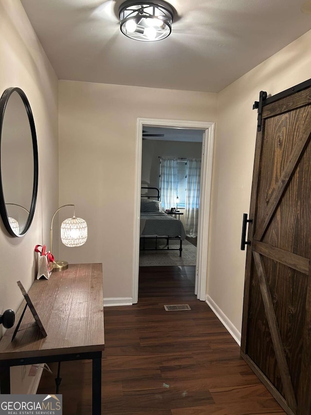 hallway featuring a barn door and dark wood-type flooring