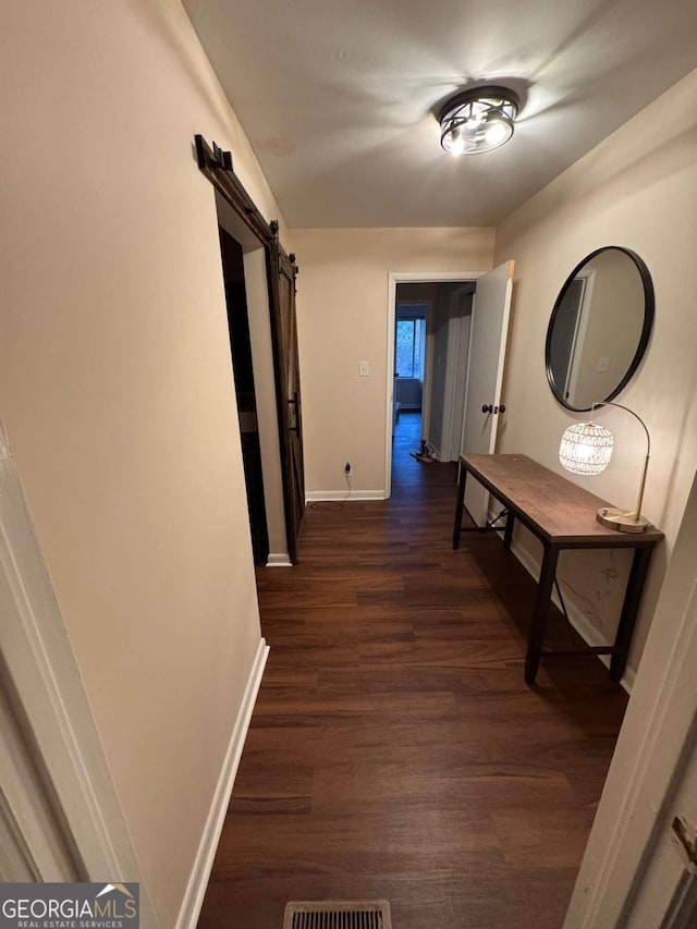 hall with a barn door and dark wood-type flooring