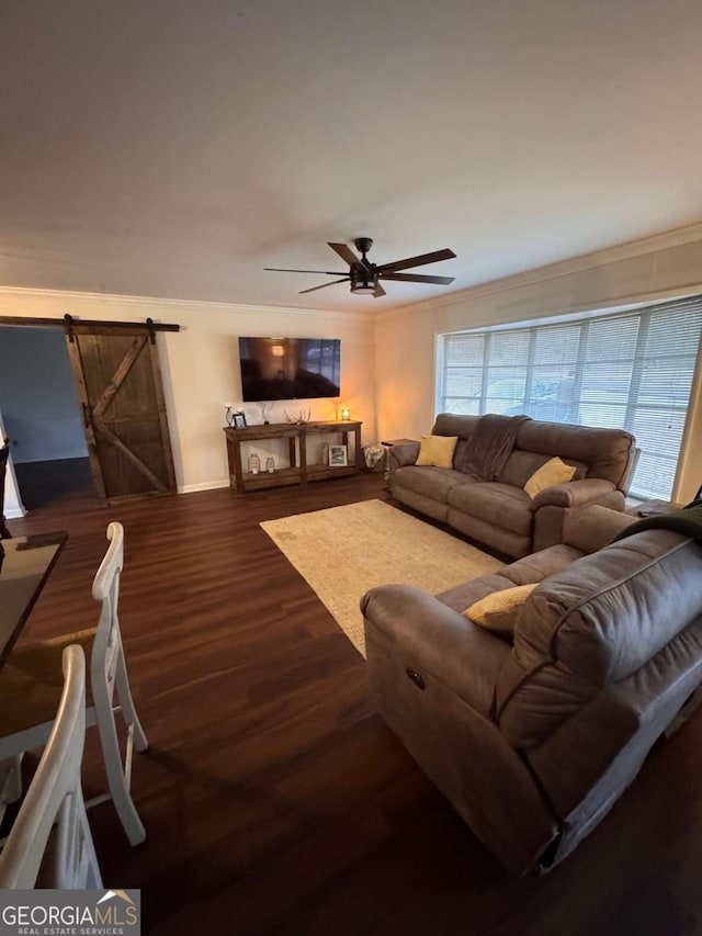 living room with dark hardwood / wood-style floors, a barn door, crown molding, and ceiling fan