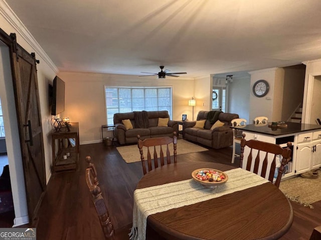 dining space featuring a barn door, dark hardwood / wood-style floors, ceiling fan, and crown molding