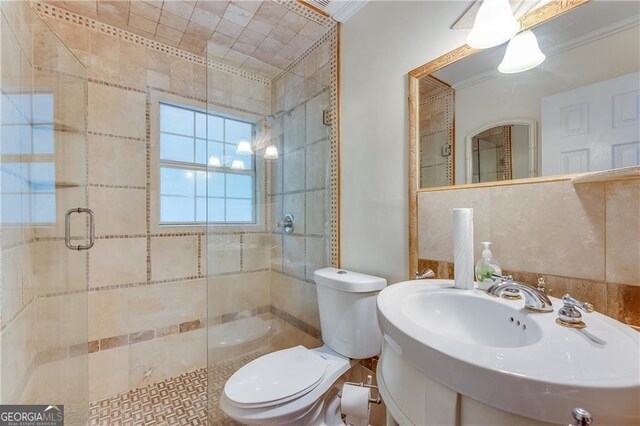 bathroom featuring an enclosed shower, sink, toilet, and crown molding