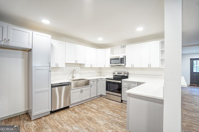 kitchen featuring white cabinets, light wood-type flooring, appliances with stainless steel finishes, and sink