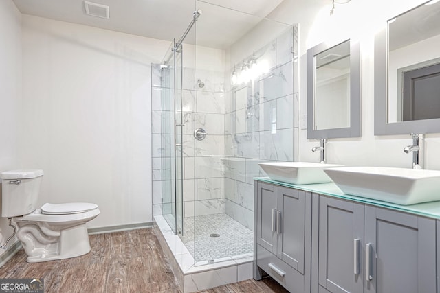 bathroom with toilet, vanity, wood-type flooring, and a shower with shower door