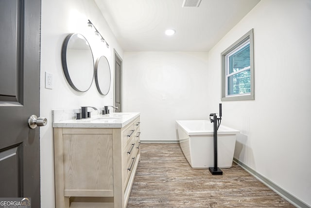 bathroom with wood-type flooring, a bathtub, and vanity