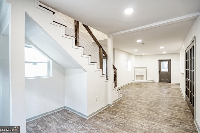 foyer entrance featuring a brick fireplace, wood-type flooring, and plenty of natural light