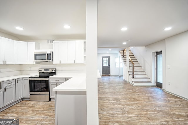 kitchen featuring light wood-type flooring, appliances with stainless steel finishes, and white cabinetry