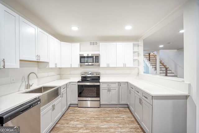 kitchen with light hardwood / wood-style floors, sink, white cabinets, and appliances with stainless steel finishes