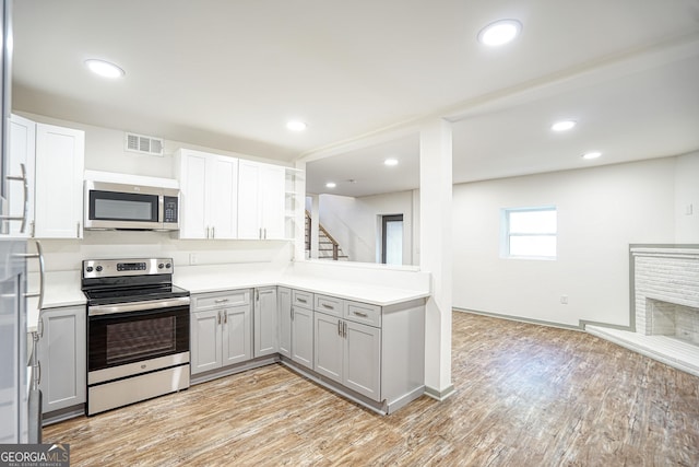 kitchen with stainless steel appliances, light hardwood / wood-style flooring, kitchen peninsula, and gray cabinets