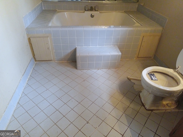 bathroom with tile patterned flooring, toilet, and tiled tub