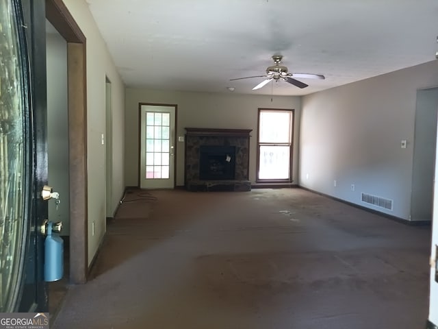 unfurnished living room featuring ceiling fan, a fireplace, a wealth of natural light, and concrete floors