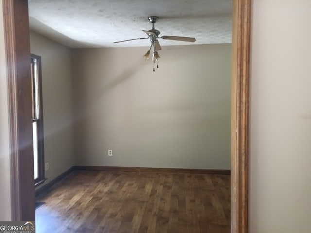 empty room featuring a textured ceiling, ceiling fan, and dark wood-type flooring