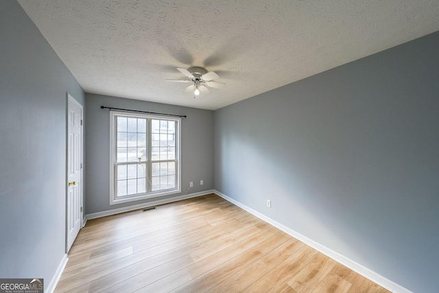 empty room with ceiling fan, light hardwood / wood-style floors, and a textured ceiling