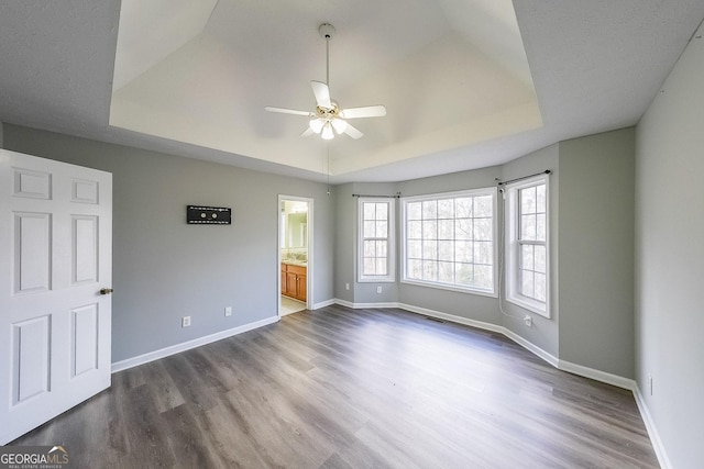 spare room with a raised ceiling, ceiling fan, and hardwood / wood-style flooring