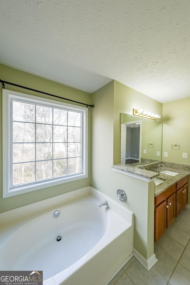 bathroom with a bathing tub, plenty of natural light, tile patterned floors, and vanity