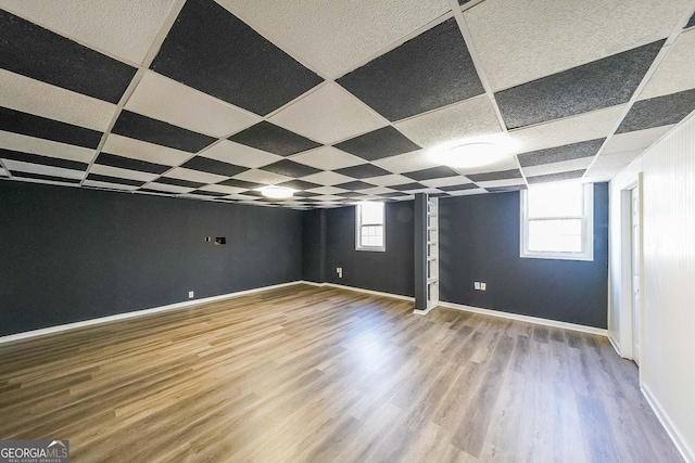 basement with plenty of natural light, a drop ceiling, and wood-type flooring