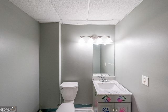 bathroom with a drop ceiling, vanity, and toilet