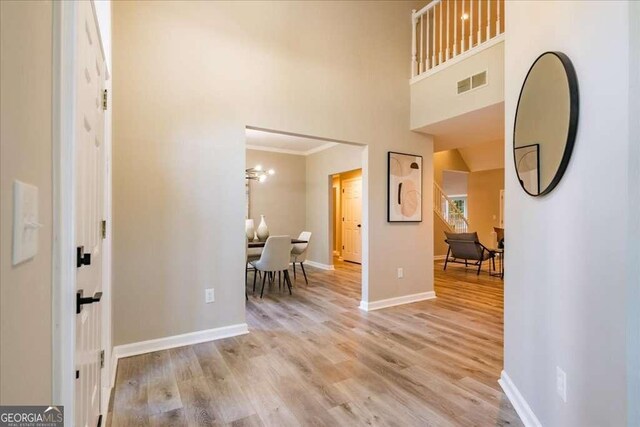 entrance foyer featuring a towering ceiling, light hardwood / wood-style floors, and ornamental molding