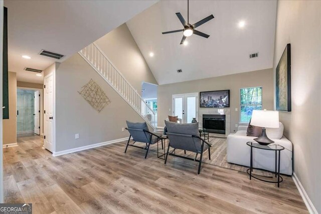 living room featuring ceiling fan, light hardwood / wood-style floors, high vaulted ceiling, and french doors