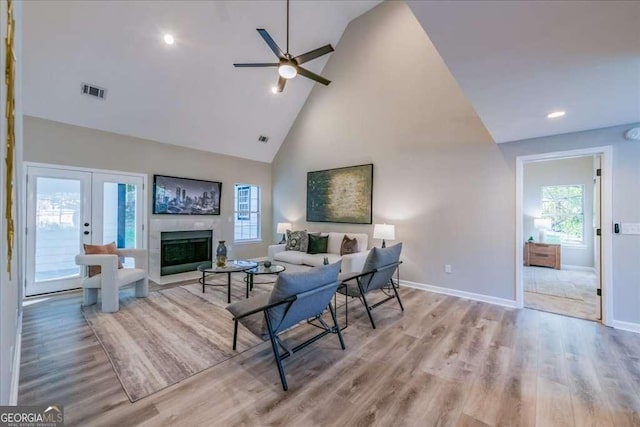 living room featuring ceiling fan, light hardwood / wood-style flooring, high vaulted ceiling, and french doors