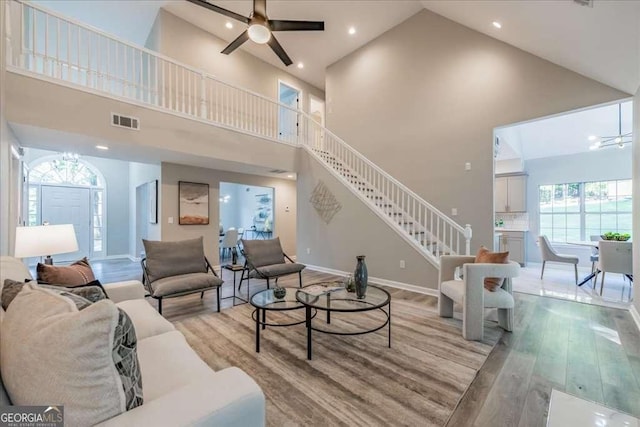 living room with ceiling fan, high vaulted ceiling, and light wood-type flooring