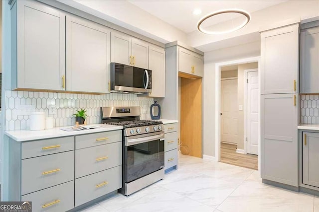 kitchen featuring backsplash, stainless steel appliances, and gray cabinets