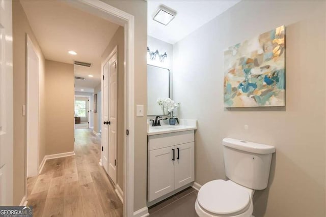 bathroom featuring wood-type flooring, vanity, and toilet