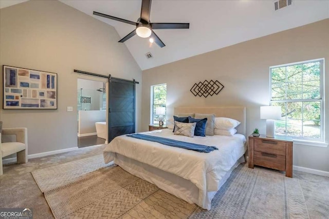 bedroom with ceiling fan, a barn door, and multiple windows