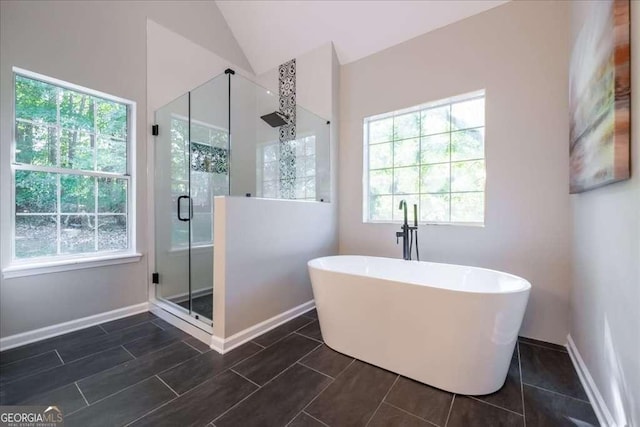 bathroom with separate shower and tub, plenty of natural light, and vaulted ceiling