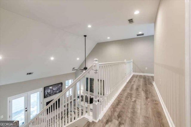 corridor featuring wood-type flooring, french doors, and vaulted ceiling