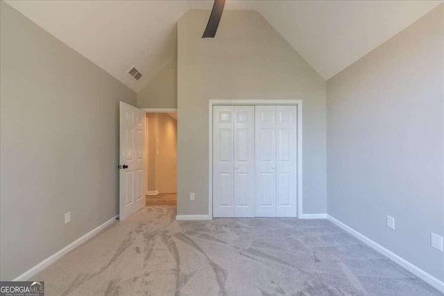 unfurnished bedroom with ceiling fan, light carpet, high vaulted ceiling, and a closet