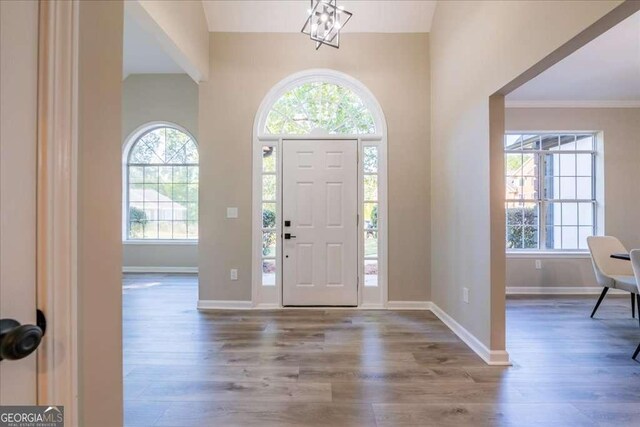 foyer entrance featuring hardwood / wood-style floors, crown molding, and an inviting chandelier