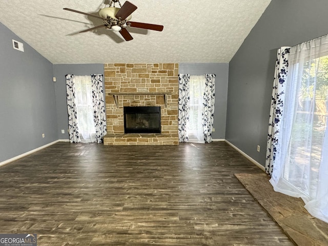 unfurnished living room with dark hardwood / wood-style flooring, a textured ceiling, a stone fireplace, and lofted ceiling