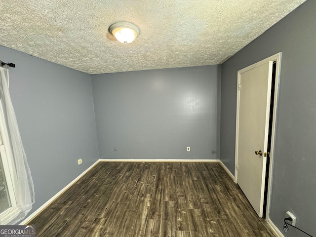 unfurnished room featuring a textured ceiling and dark wood-type flooring