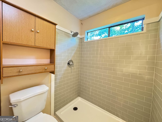 bathroom featuring a tile shower, a textured ceiling, and toilet