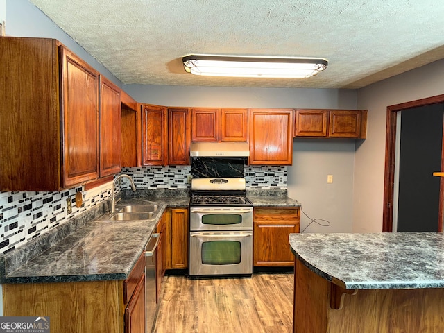 kitchen featuring a textured ceiling, light hardwood / wood-style floors, sink, and stainless steel appliances