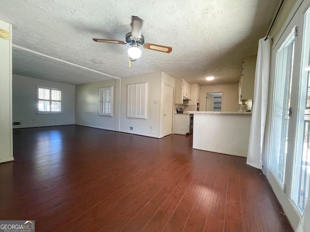 unfurnished living room featuring ceiling fan, dark hardwood / wood-style flooring, and a textured ceiling