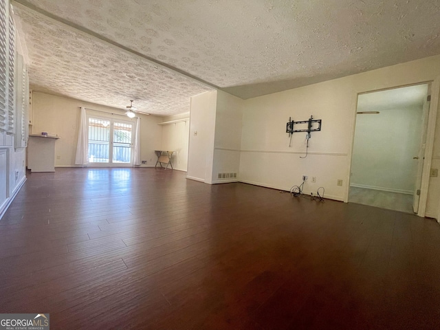 spare room featuring ceiling fan, dark wood-type flooring, and a textured ceiling