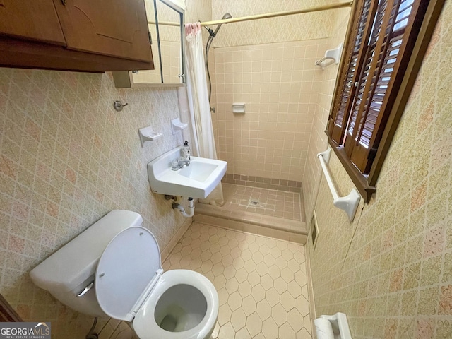 bathroom with curtained shower, sink, tile patterned flooring, toilet, and tile walls