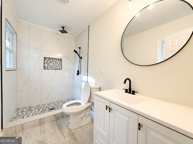 bathroom with a tile shower, vanity, and toilet