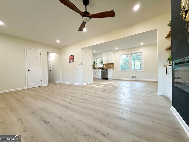 unfurnished living room with ceiling fan, sink, and light hardwood / wood-style floors