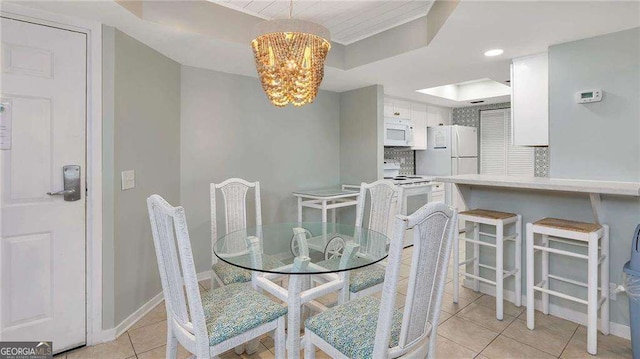 tiled dining area with a tray ceiling and a notable chandelier