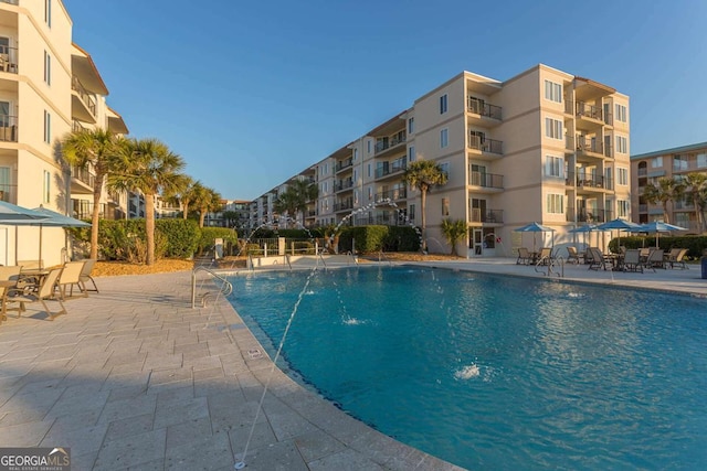 view of swimming pool with pool water feature and a patio