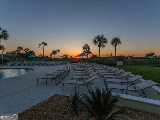 pool at dusk featuring a patio