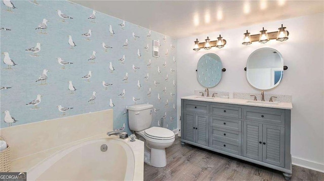 bathroom with hardwood / wood-style floors, vanity, toilet, and a bath