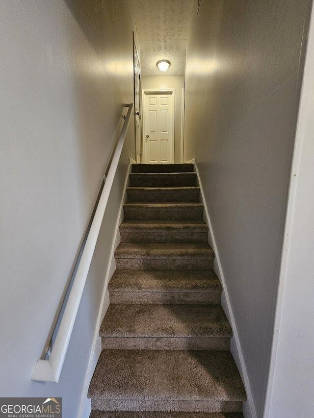 stairs with a textured ceiling