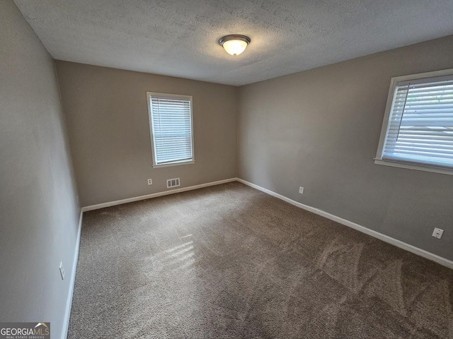 carpeted spare room with a textured ceiling