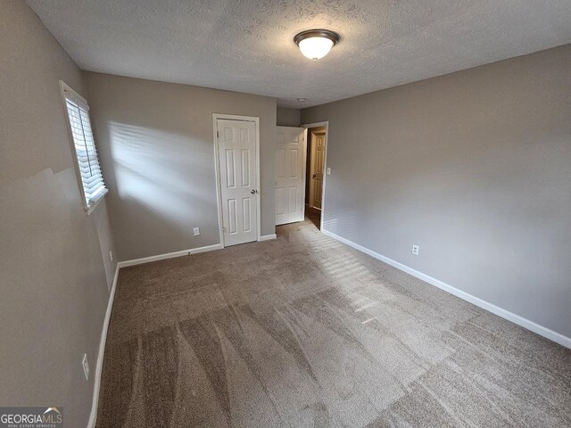 empty room with a textured ceiling and carpet floors